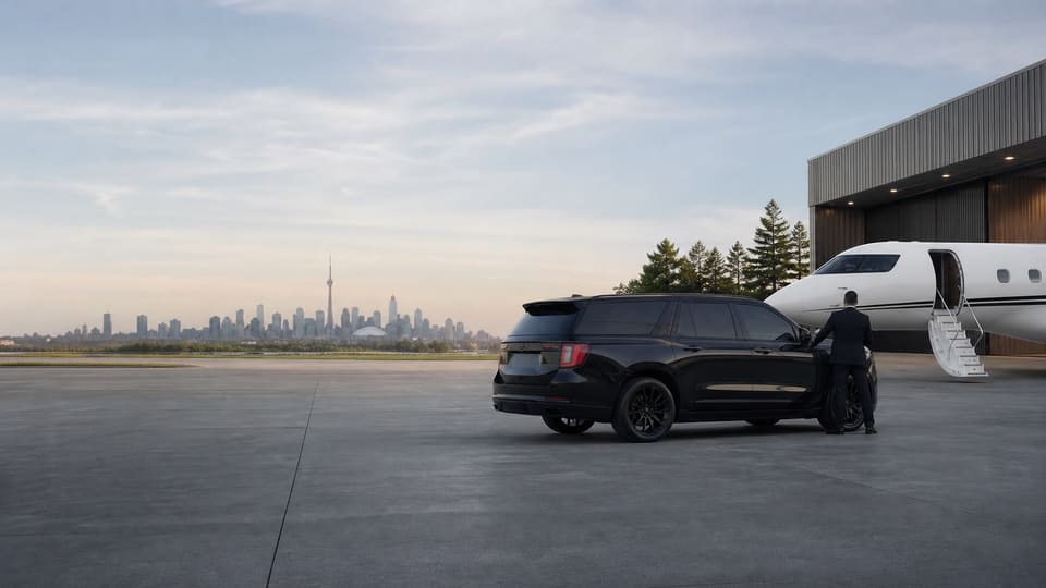 Executive SUV and chauffeur waiting beside a private jet